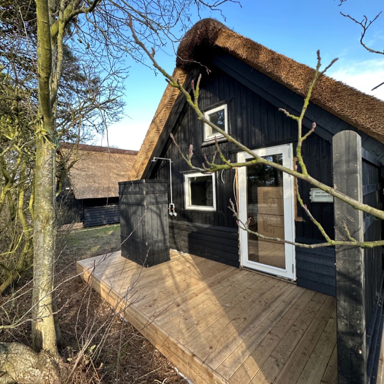 Schwarzer Sichtschutzzaun Rustik aus Nadelholz mit Reetdach auf Holzterrasse.