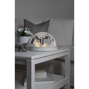 Konstsmide LED Holzsilhouette Häuser und Rentiere, warmweißes Licht, auf einem Tisch.