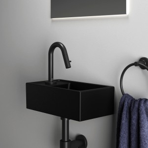 Schwarzer Ideal Standard Designsiphon G 1 1/4 am Waschbecken mit Handtuchring.