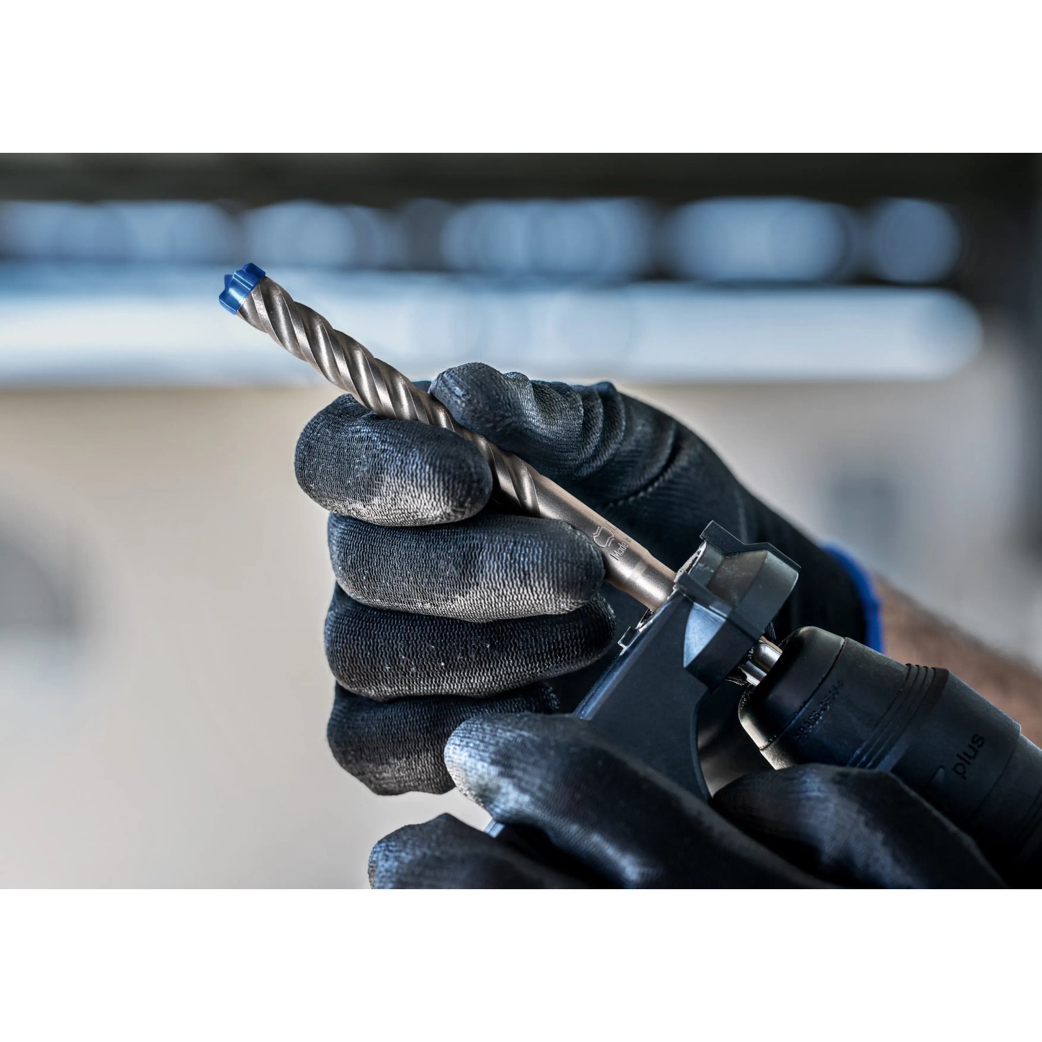 Bosch Expert Hammerbohrer SDS Plus-7X (13mm) im Bohrfutter, gehalten von Hand mit Arbeitshandschuh.