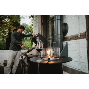 Schwarzes Enders Gas-Terrassenfeuer Nova mit Glaszylinder und Ablagefläche. Stimmungsvolles Ambiente im Garten.