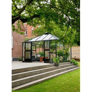 Juliana Gewächshaus Oase 13 Anthrazit im Garten mit Pflanzen und Sitzbereich.