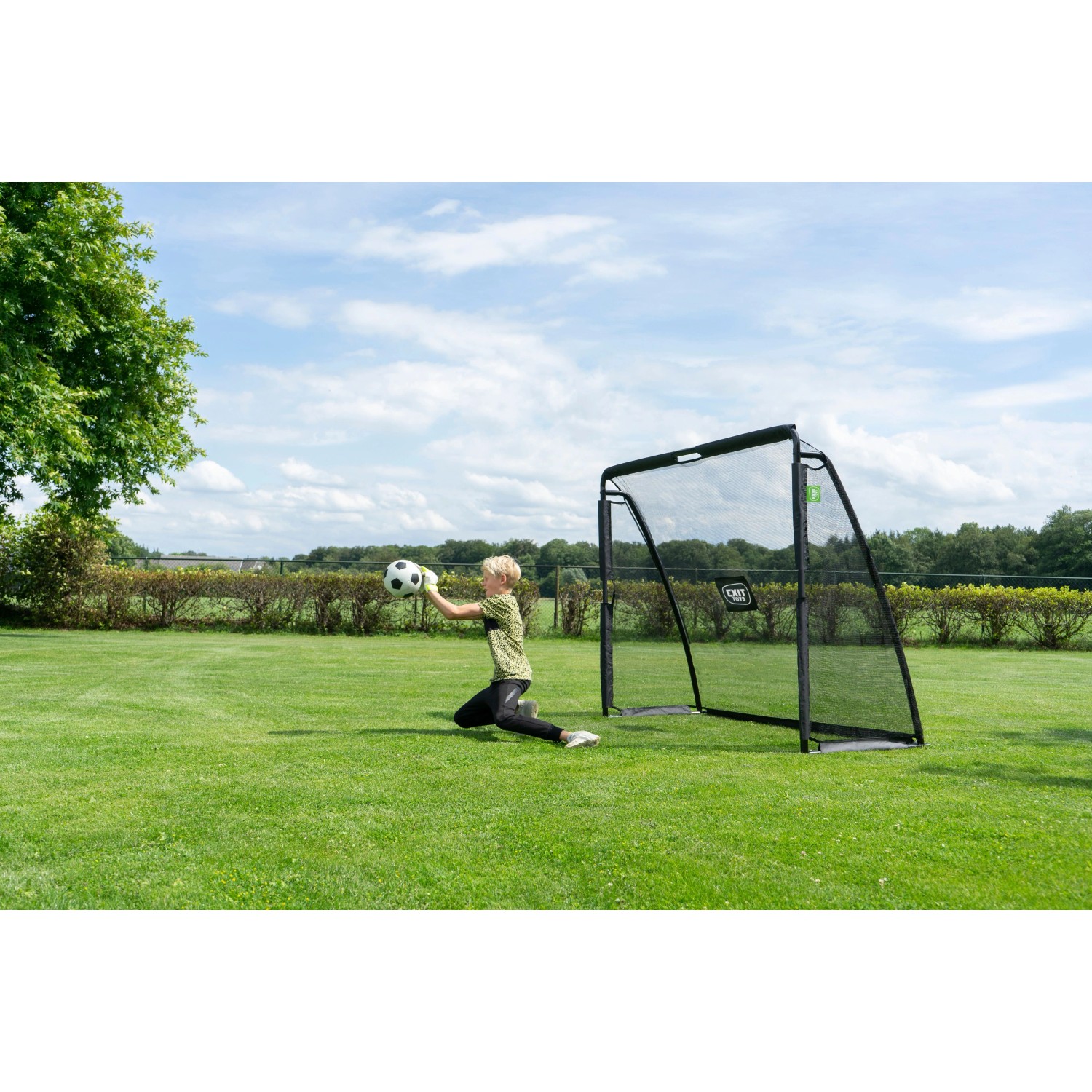 Schwarzes EXIT Coppa Fußballtor aus Stahl im Garten, ein Kind fängt den Ball. Ideal für Sport & Fitness.