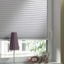 Weißes Gardinia EasyFix Thermo-Plissee am Fenster, höhenverstellbar mit Bedienschienen.