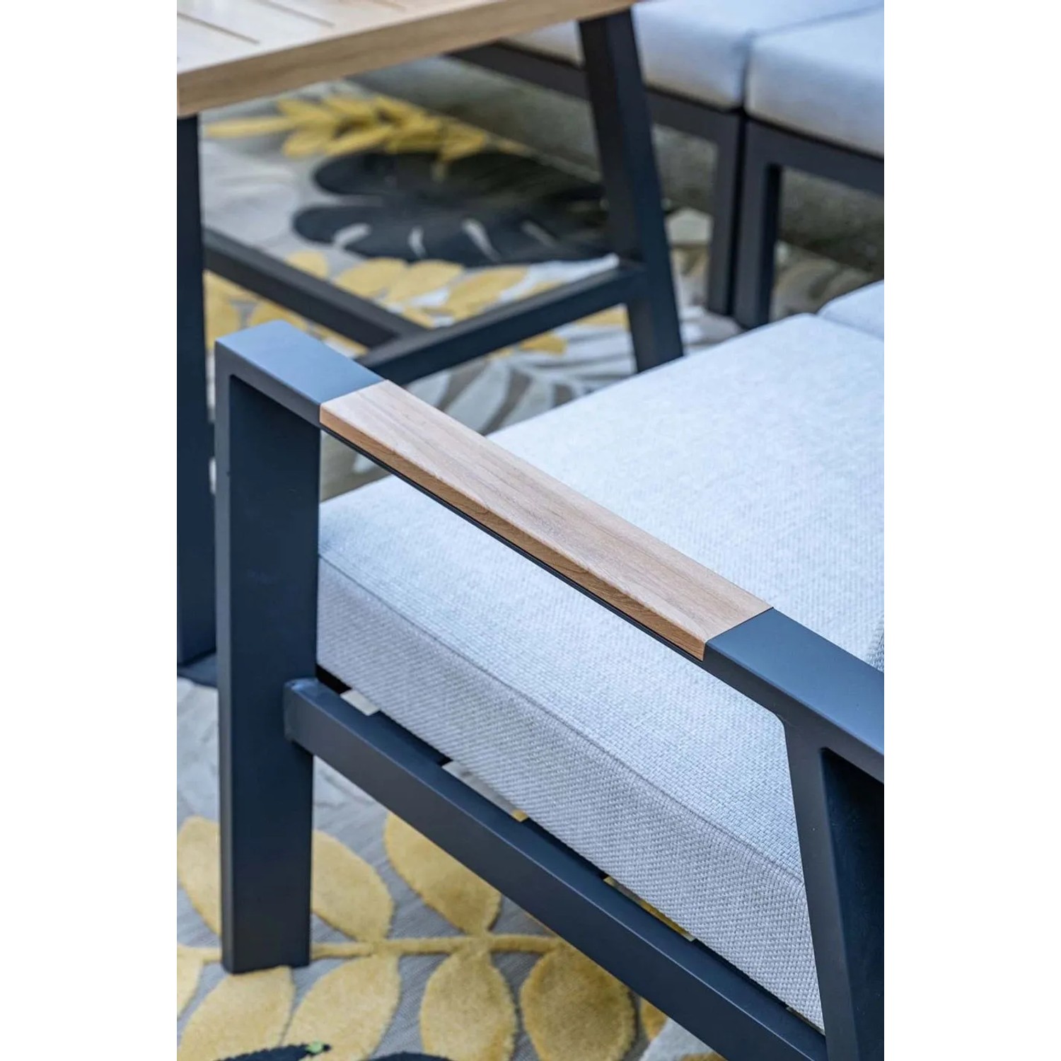 Detail der Elati Gartenlounge: Dunkle Aluminium-Armlehne mit Teak-Look-Akzent und hellgrauem Kissen. Modernes Design.