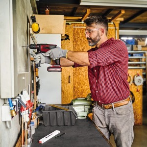 Mann bohrt mit Einhell Akku-Schlagbohrmaschine TE-ID 18 Li - Solo in Werkstatt.