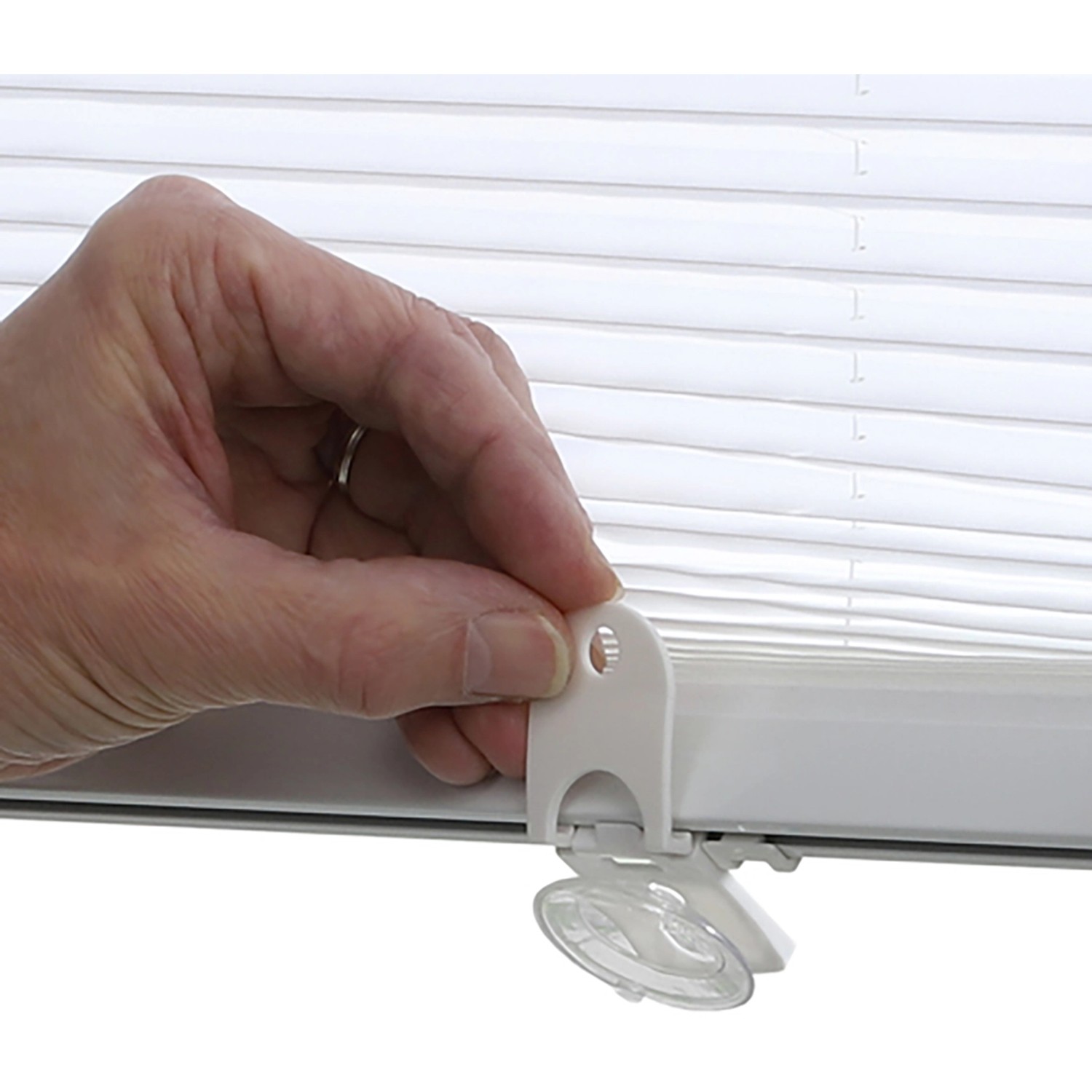 Weißes Gardinia Dachfenster-Plissee mit Saugnäpfen in der Hand, Detailaufnahme.