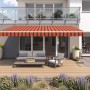 Wismar Gelenkarmmarkise Classic, 300x200 cm, orange-braun, montiert an Hauswand über Terrasse.