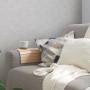 Helle, leicht strukturierte Ethno Vliestapete in Weiß und Grau an der Wand hinter einem Sofa.