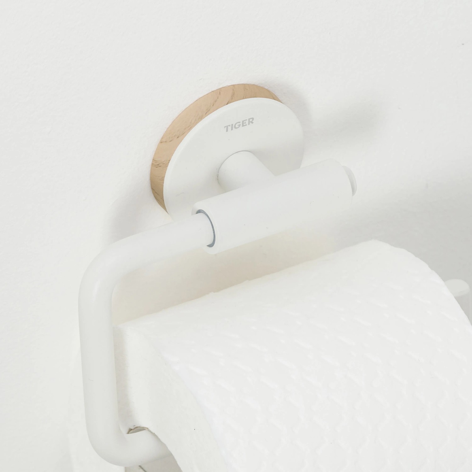 Weißer Tiger Toilettenpapierhalter Urban ohne Deckel mit Holz-Akzent an weißer Wand.