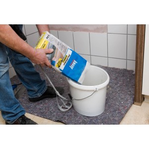 Anwender schüttet grauen Knauf Flexkleber Schnell aus einem 5 kg Sack in einen Eimer.