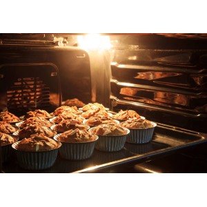 Backofen mit Muffins in silbernen Förmchen auf einem Backblech.