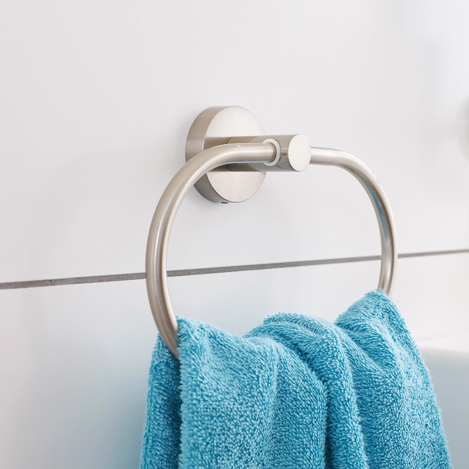 Tesa Smooz Handtuchring, verchromt, mit blauem Handtuch an weißer Wand.