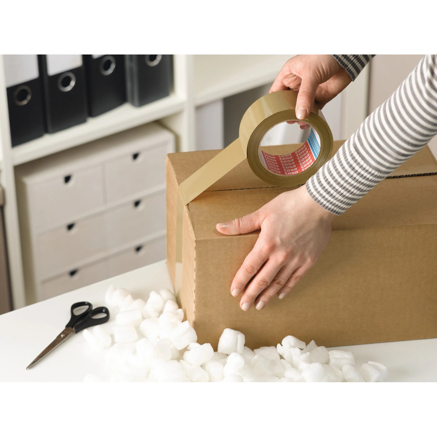 Tesapack Strong Packband braun beim Verkleben eines Kartons.