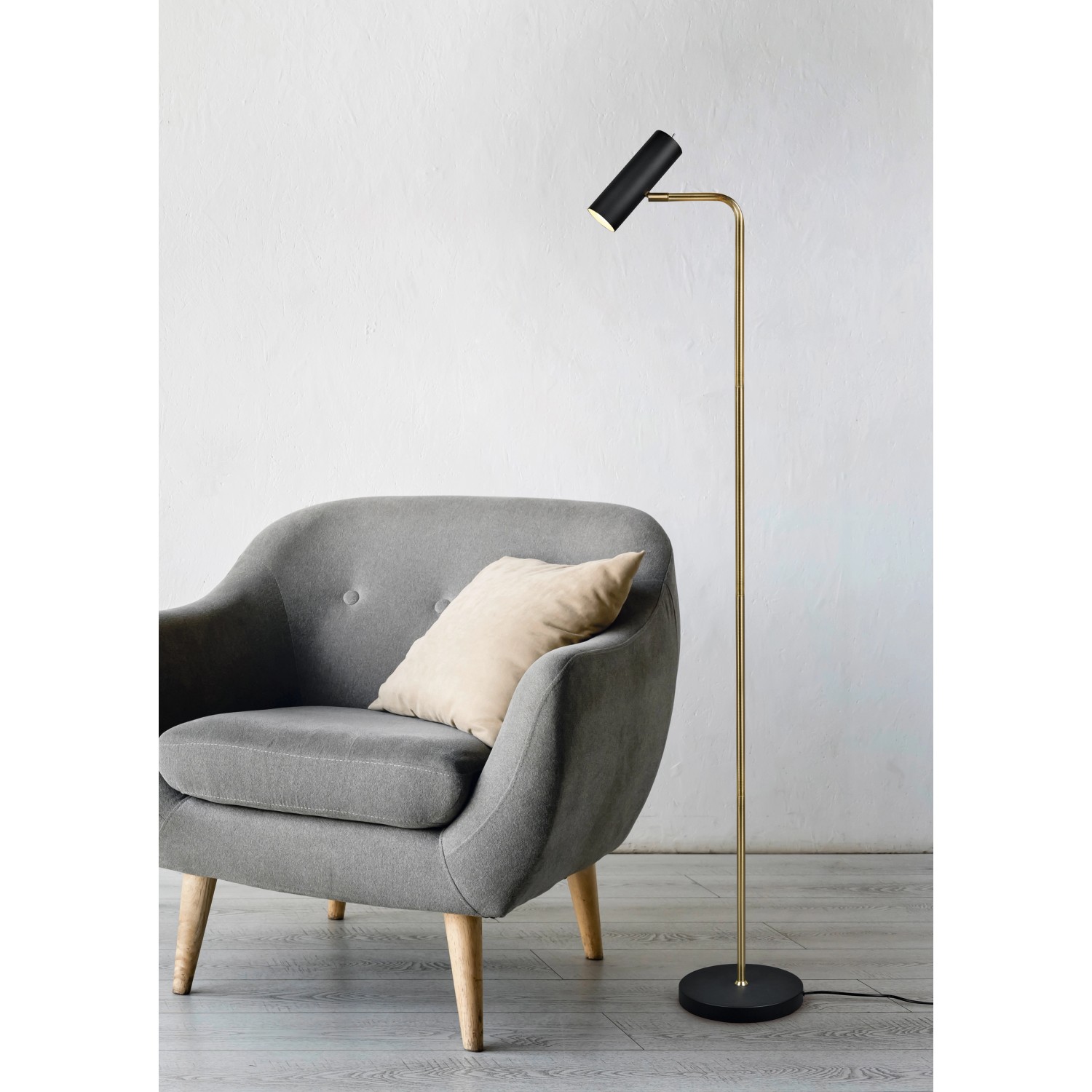 Moderne Trio LED-Stehleuchte Marley in Messing matt neben Sessel.