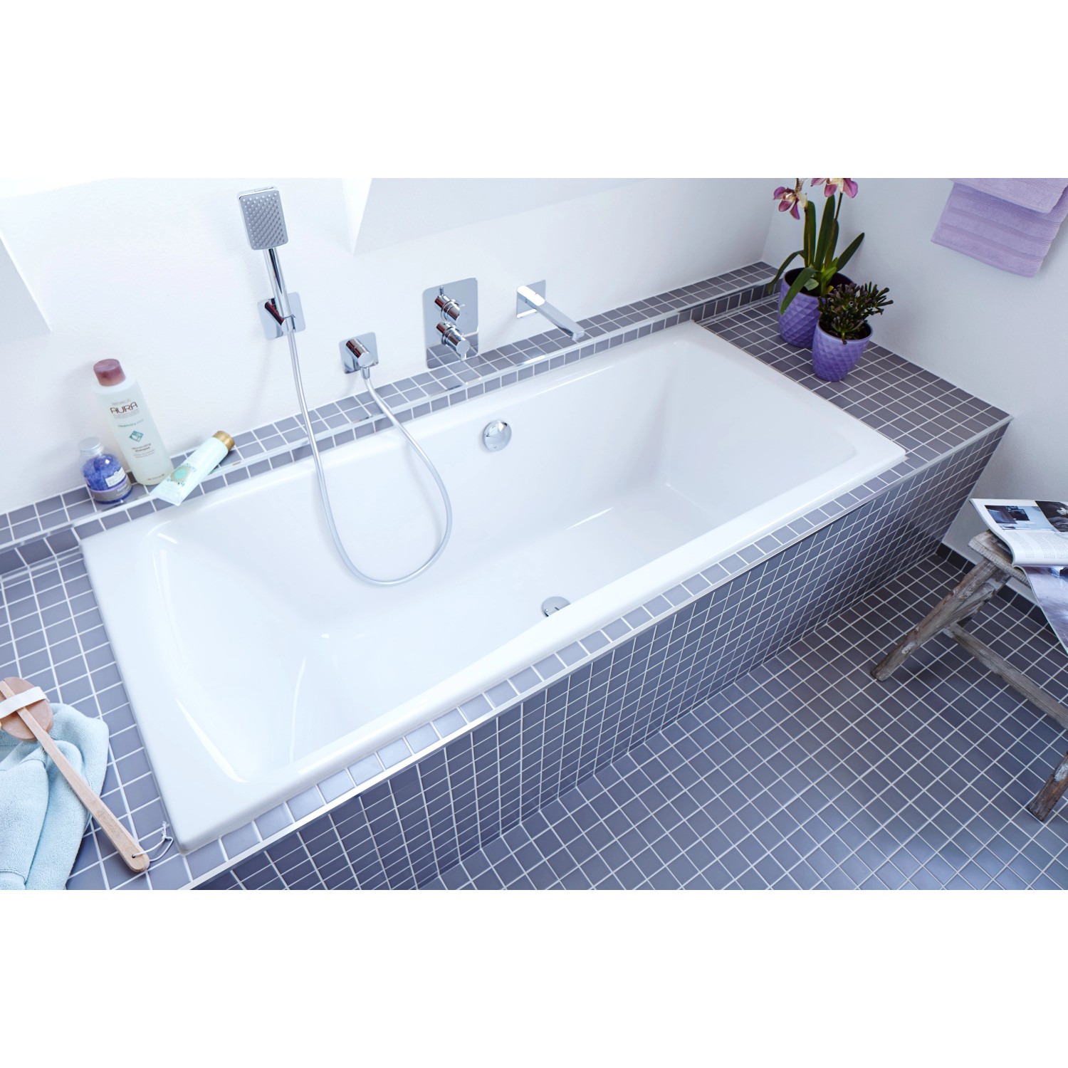 Eingebaute Badewanne in Weiß mit grauen Fliesen und Armaturen im Badezimmer.