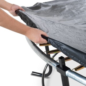 Schwarze EXIT Premium Trampolin Abdeckplane (Ø305cm) wird über ein Trampolin gezogen.