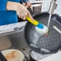 Gelbe Spülbürste Dish Daddy im Einsatz beim Abwaschen einer Pfanne in der Küche.