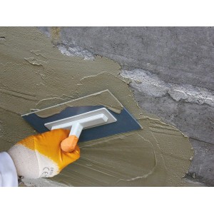 Auftragen der Ravenit D Hellgrau Dichtungsschlämme mit einer Glättkelle auf eine Betonwand.