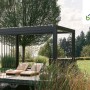 Biohort Pergola 4,5x3,5m in Quarzweiß auf Holzdeck mit zwei Liegen im Garten.