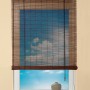 OBI Bambus-Raffrollo Teak, 100x160 cm, am Fenster mit Blick auf blauen Himmel.