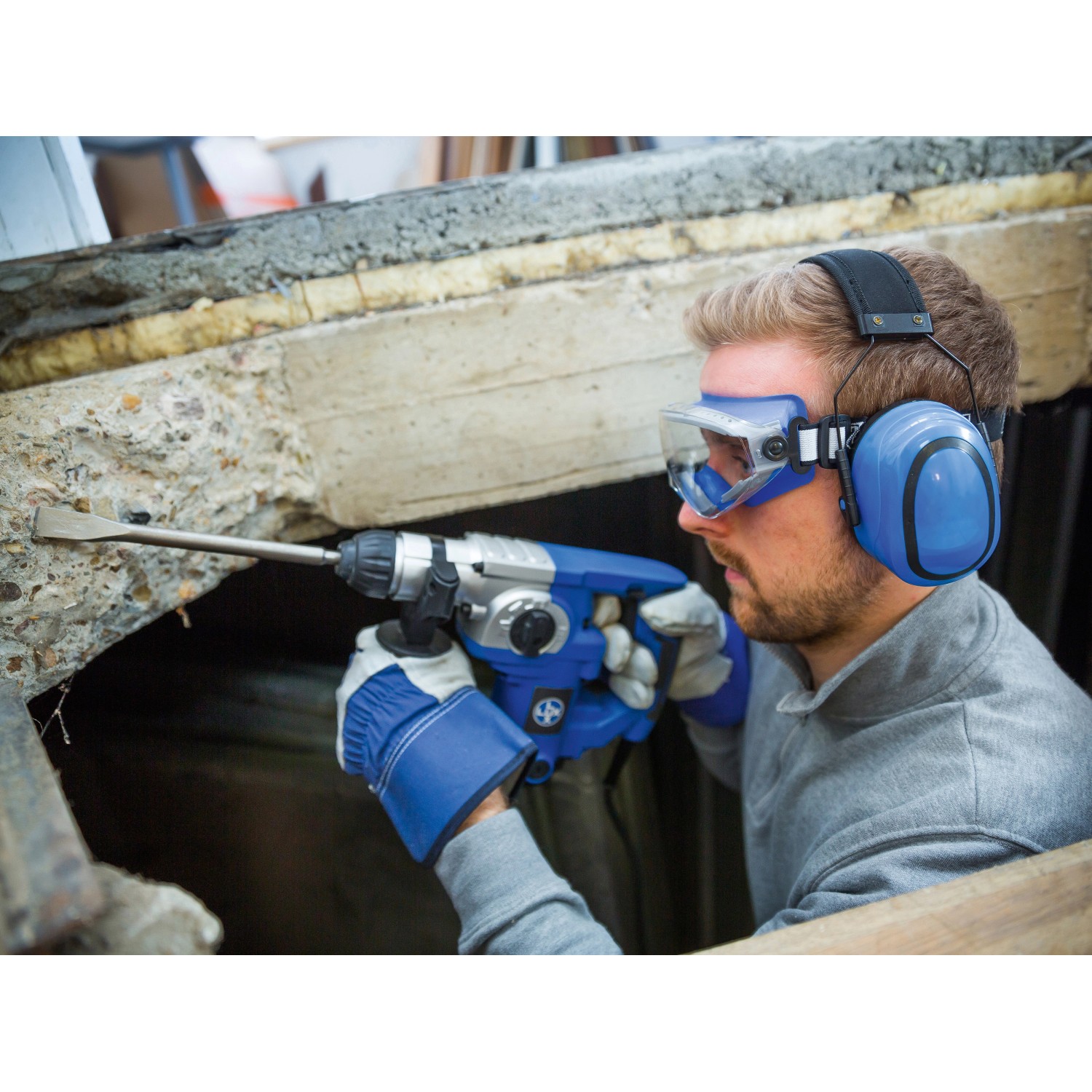 Mann mit blauem LUX Kapselgehörschutz beim Bohren. Gehörschutz für Heimwerker.