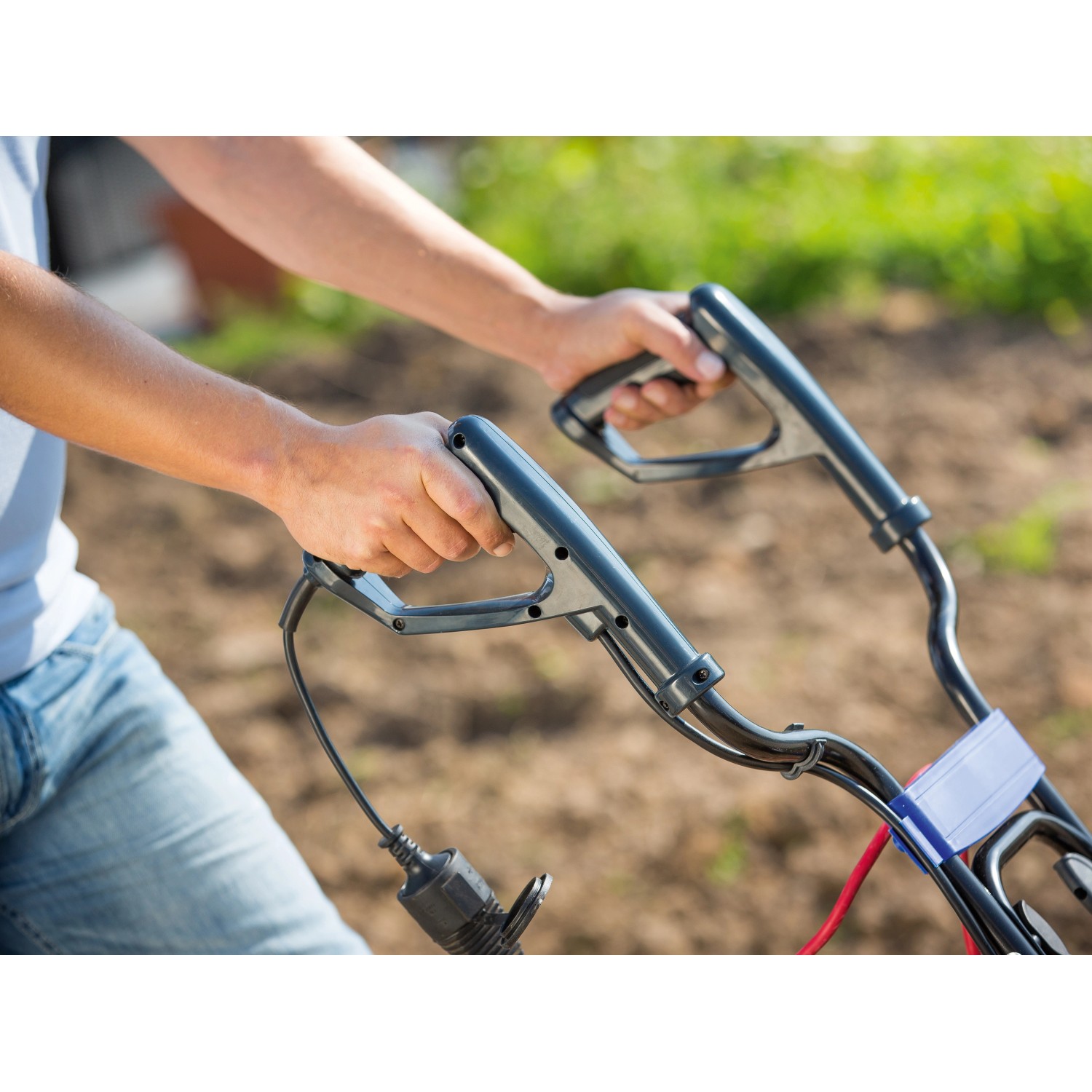 Detailaufnahme: Hände bedienen die LUX Elektro-Bodenhacke E-BH 1400-43 im Garten.