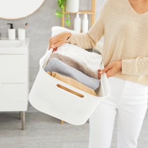 Frau trägt weißen Rotho Wäschekorb Brisen 41 l mit Wäsche im Badezimmer.