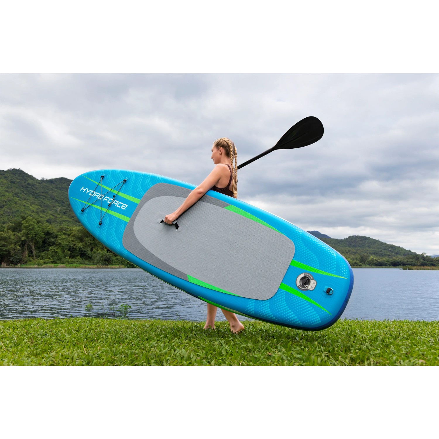 Frau trägt blaues Bestway SUP Allround Board Aqua Journey mit Paddel am See.