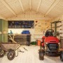 Innenansicht: Hellgraues Palmako Gerätehaus Lucas mit Gartengeräten und Rasentraktor.