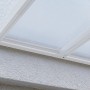 Detailaufnahme: Weiße Gutta Terrassenüberdachung mit Polycarbonatplatten an Hauswand montiert.