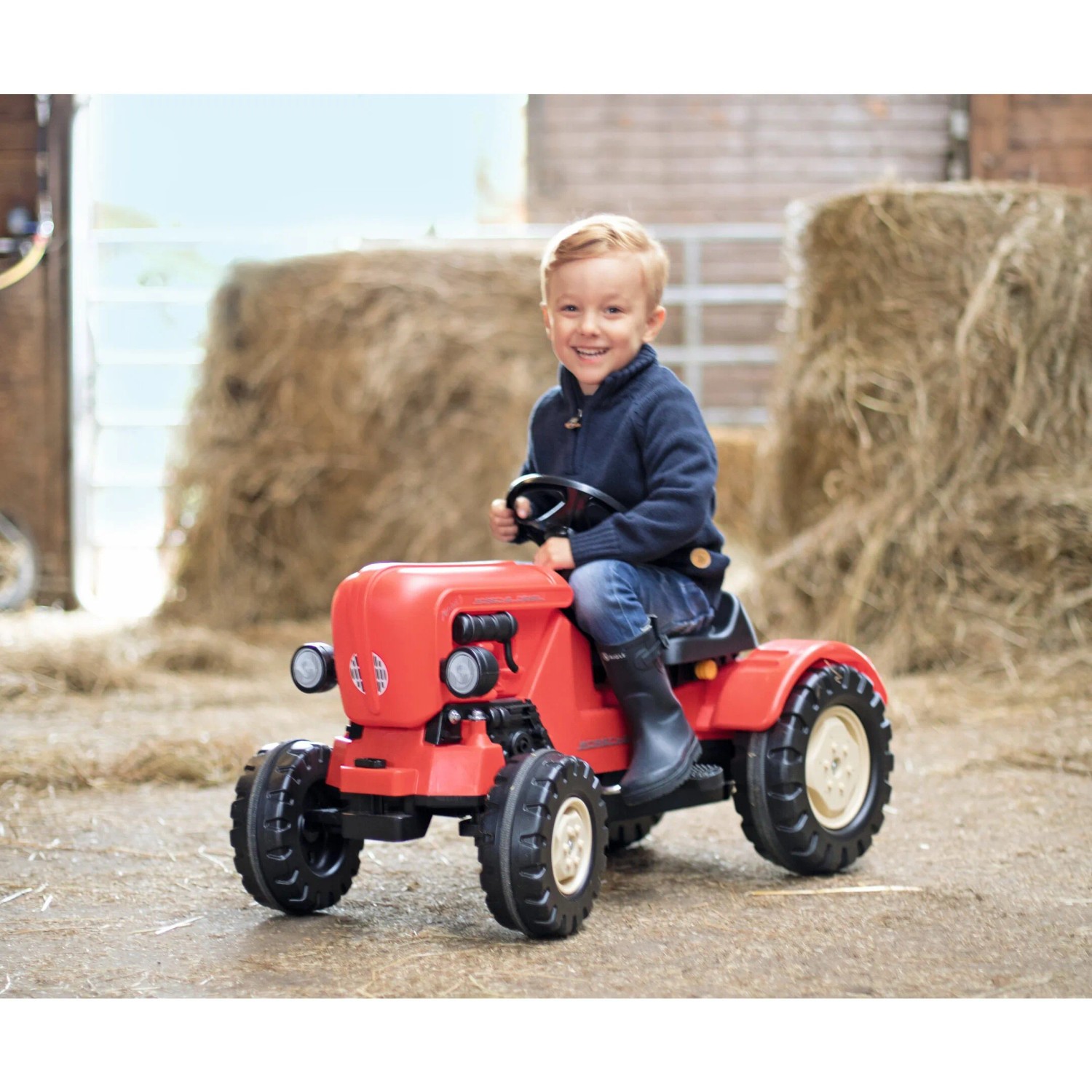 Roter BIG Trettraktor Porsche Diesel Junior mit Kind auf einem Bauernhof.