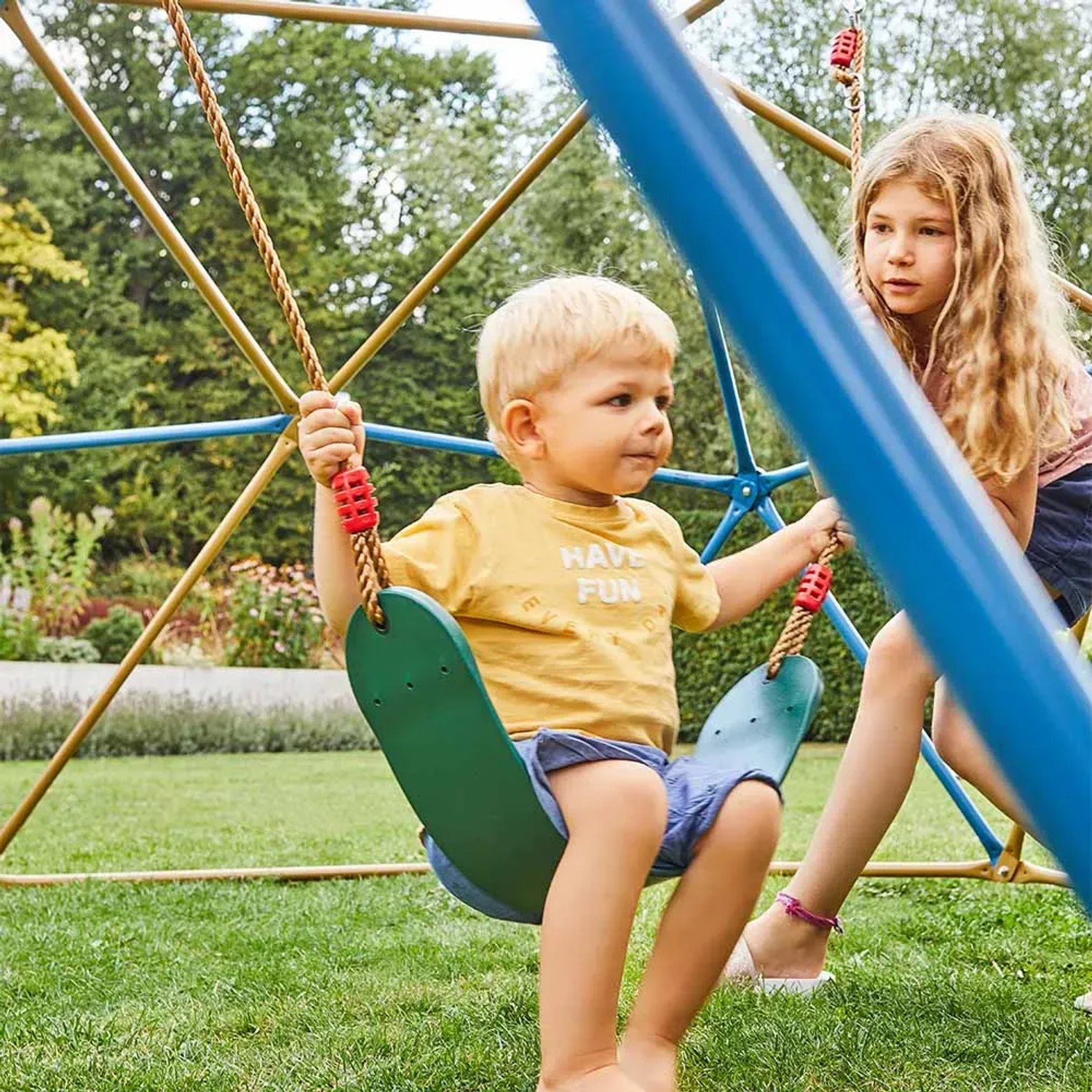 Home Deluxe Klettergerüst Matti mit Schaukel und Kindern beim Spielen im Garten.