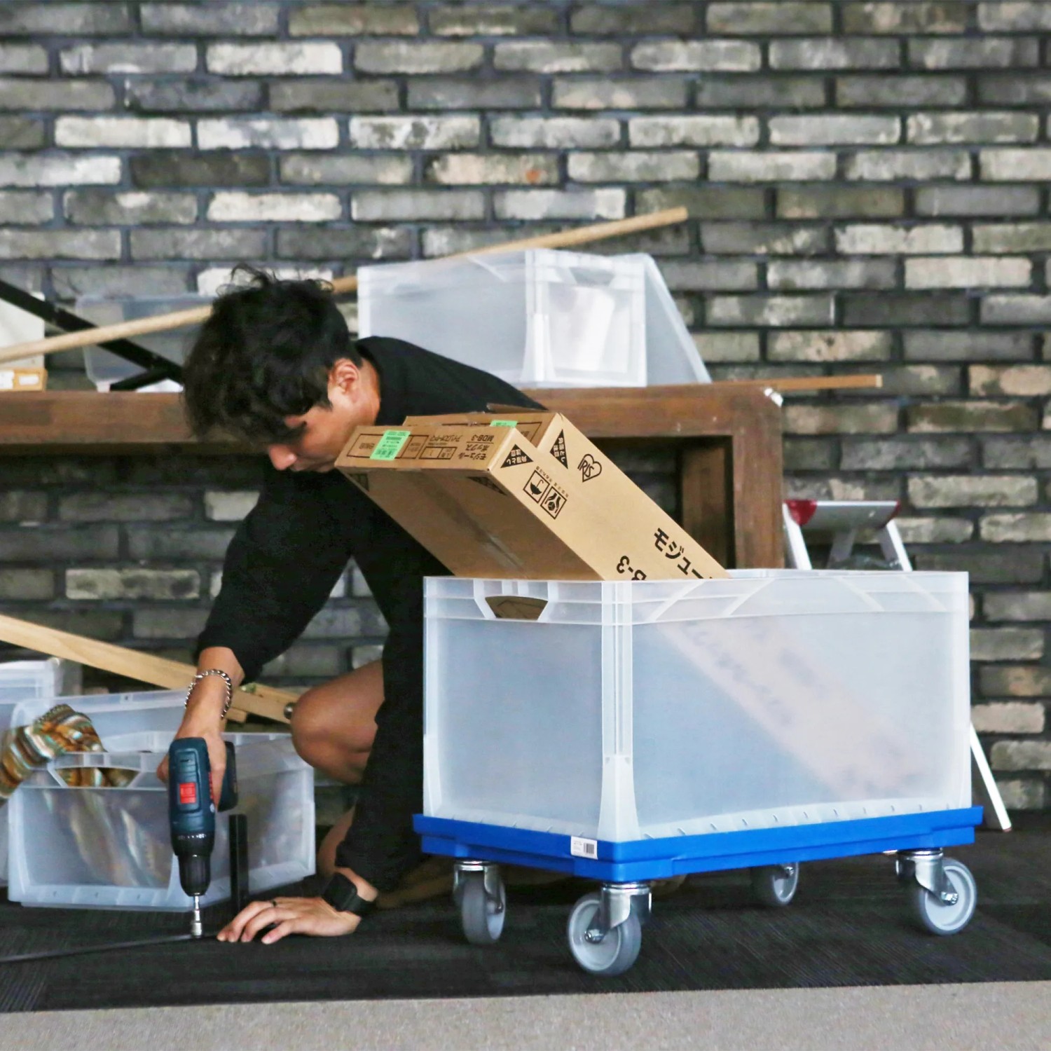 Eurobox System Box Grau 60x40x32 cm auf Rollen mit Person und Werkzeug.