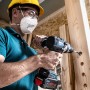Handwerker bohrt mit Bosch Flachfräsbohrer Löcher in Holzbalken.
