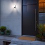 Bosch Smart Home Eyes II Außenkamera in Silber an Hauswand mit Tür und Pflanzen.