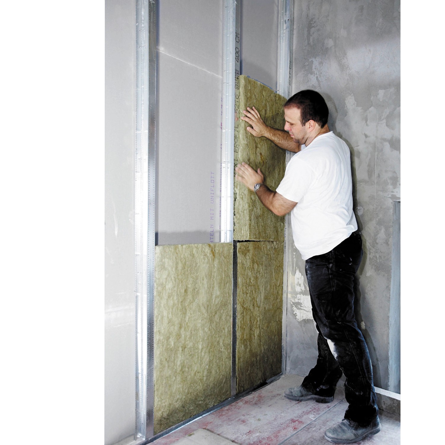 Ein Mann montiert Rockwool Sonorock Trennwandplatten (40mm) aus Steinwolle in einer Wand.