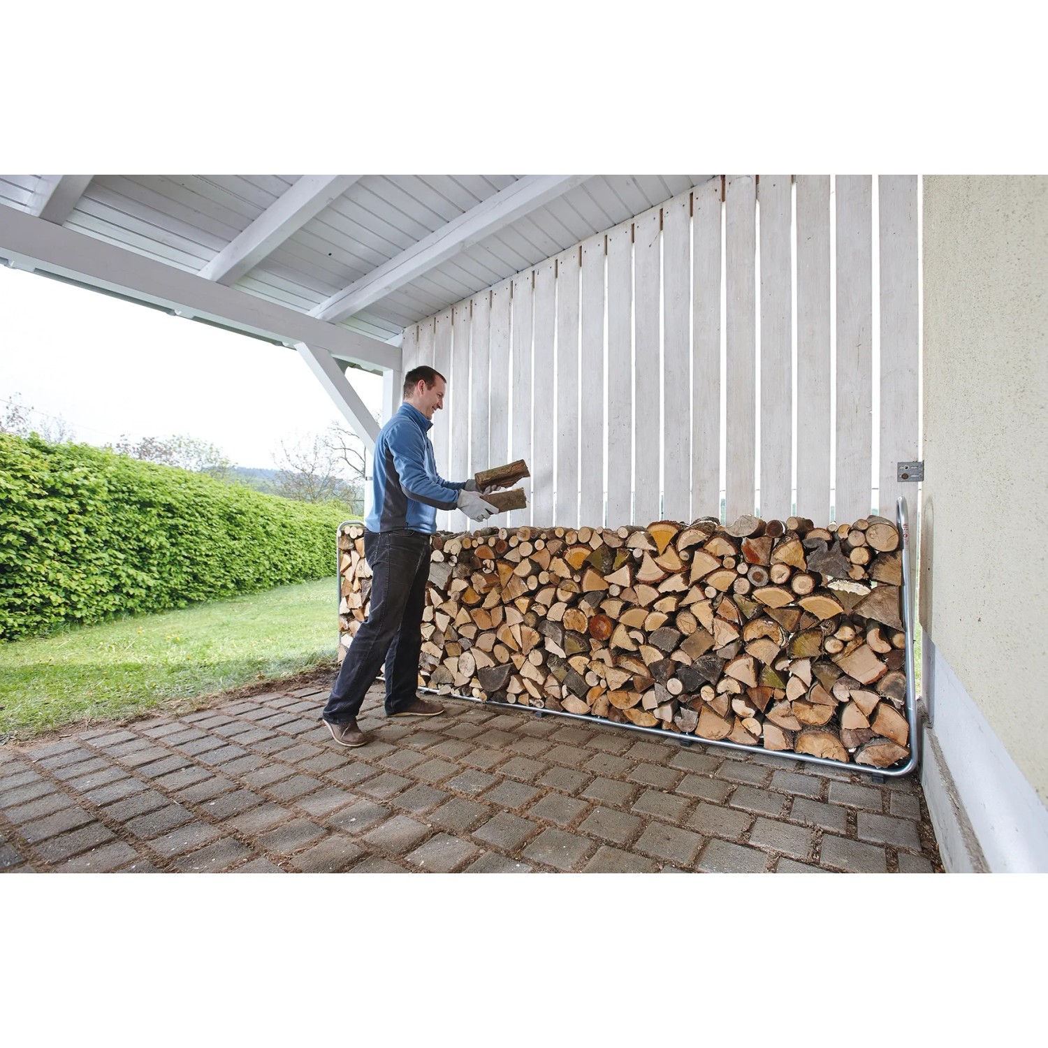 Wolfcraft Kaminholzregal Modular XXL mit Holzscheiten und Person beim Einlagern.