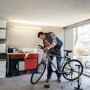 Mann repariert Fahrrad unter Osram LED-Leuchtstofflampe in Garage. Kaltweißes Licht.