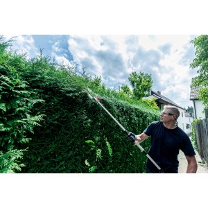 Mann schneidet hohe Hecke mit Metabo Heckenscheren-Aufsatz MA-HS 50.