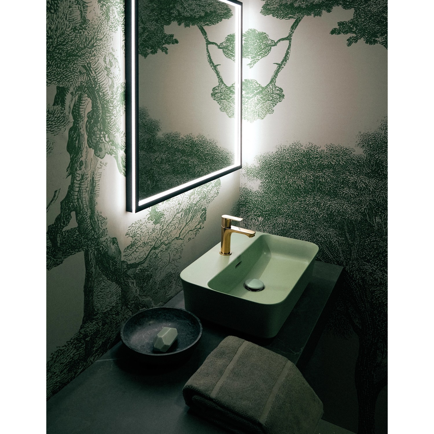 Ideal Standard Connect Air Slim Waschtischarmatur in gebürstetem Gold vor grünem Waschbecken.