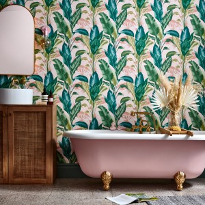 Badezimmer mit rosa Badewanne und Envy Vliestapete Leaf It Out Sunrise mit Blättern in Rosa und Grün.