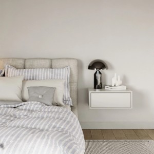 Weißer Selsey Framme Nachttisch hängend mit Schublade, neben einem Bett im Schlafzimmer. Modernes, minimalistisches Design.
