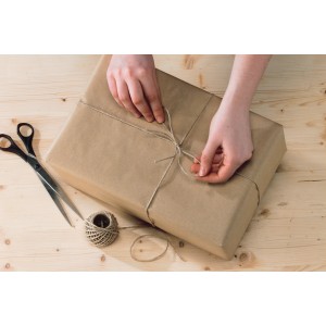 Paket wird mit beiger Paketkordel aus dem 3er Set verschnürt, Schere liegt bereit.