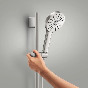 Hand verstellt silberne Handbrause an Brausestange. Vitalio Joy+ Brausestangenset für flexible Duschhöhe.