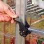 Detailaufnahme: Hand öffnet Tür des Palram Canopia Hybrid Gewächshauses mit schwarzem Griff.