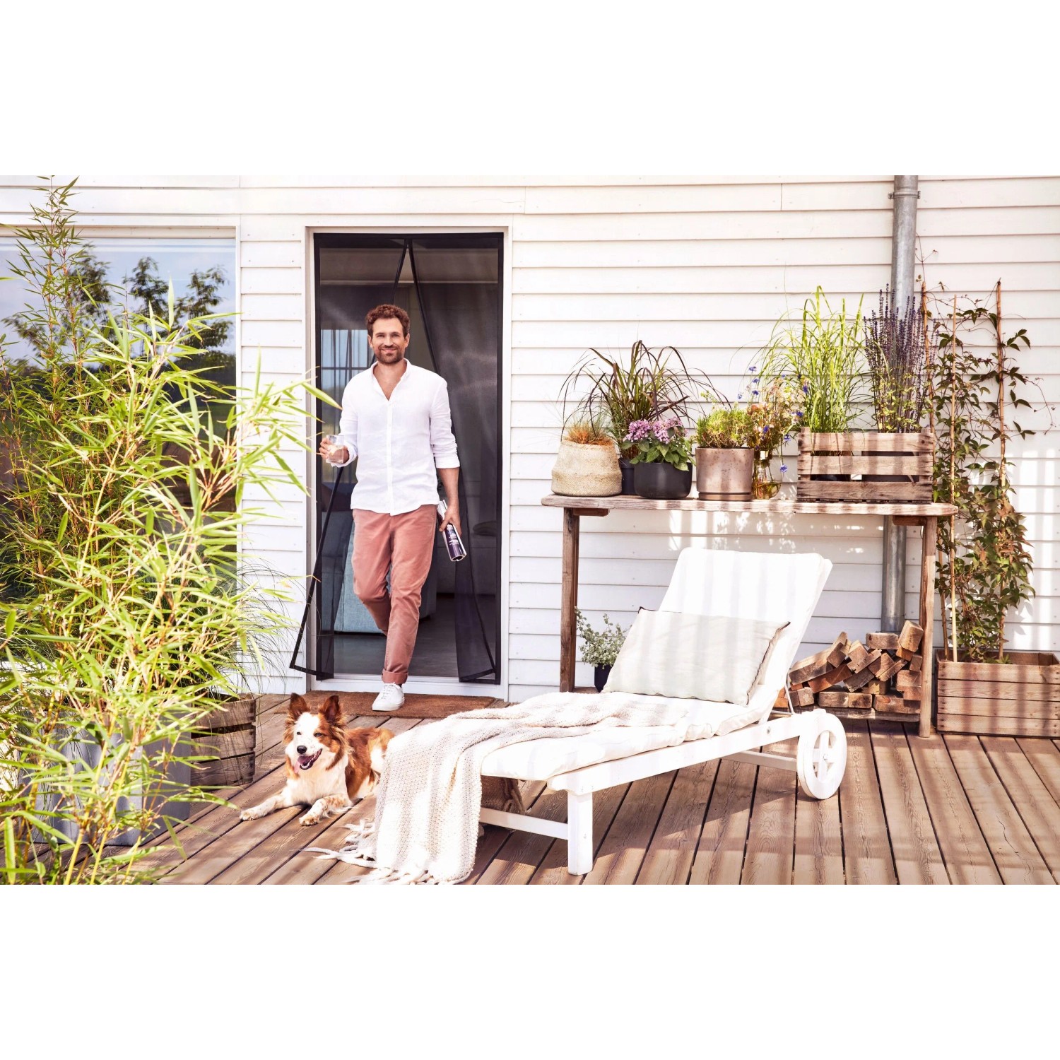 tesa® Insect Stop Magnetvorhang Tür, anthrazit, mit Mann und Hund auf Terrasse.