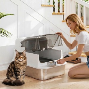 Weiße PawHut XXL Edelstahl Katzentoilette mit offener Klappe, Frau reinigt mit Schaufel, Katze daneben.