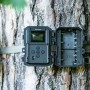 Bresser Wildkamera, 5-20 MP, am Baum befestigt, Gehäuse geöffnet mit Batteriefach sichtbar.