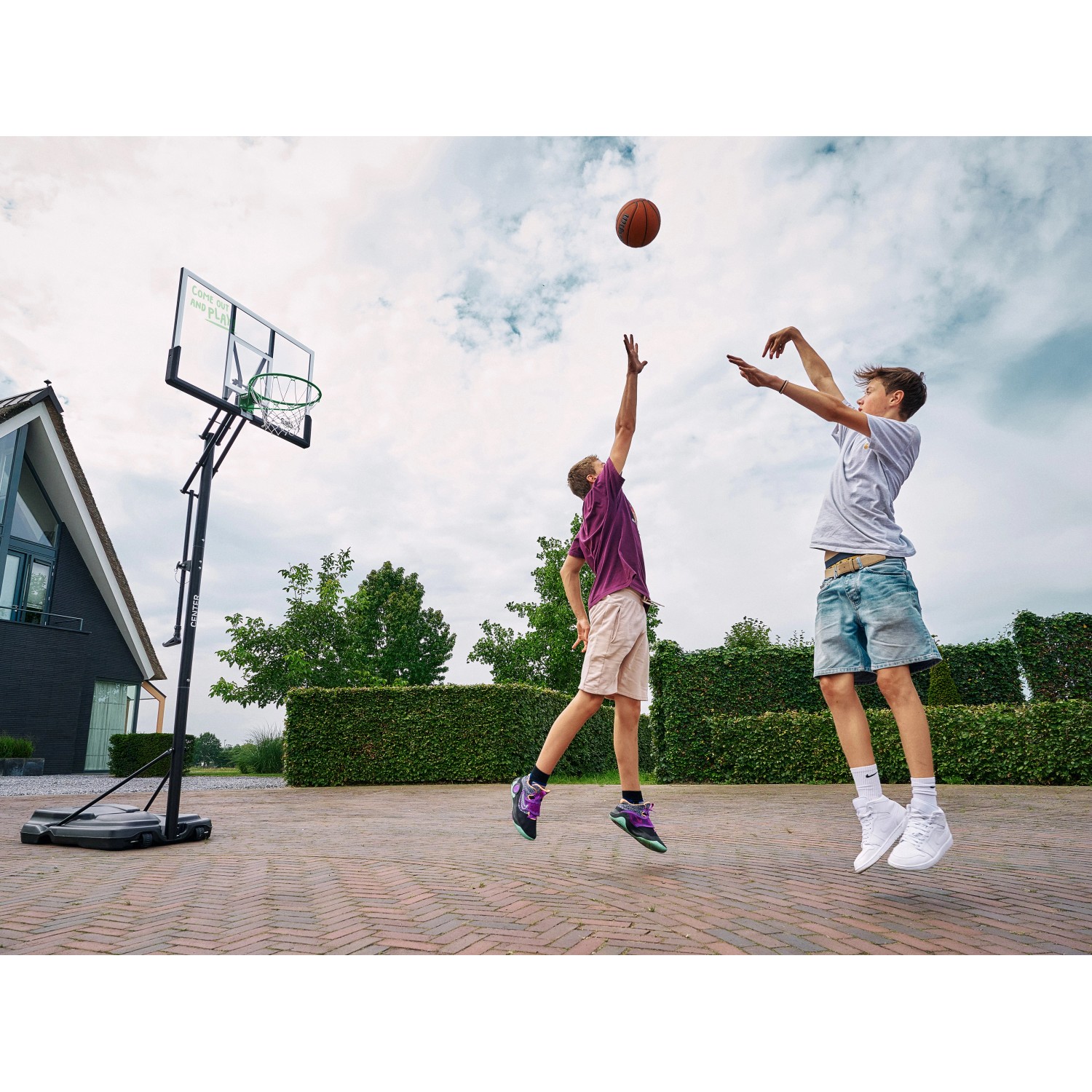 Salta Basketballständer Center im Einsatz: Zwei Jugendliche spielen Basketball im Freien.